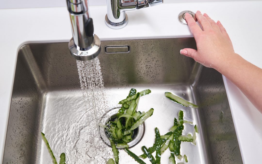 A homeowner letting food scraps go down the garbage disposal for dinner cleanup.